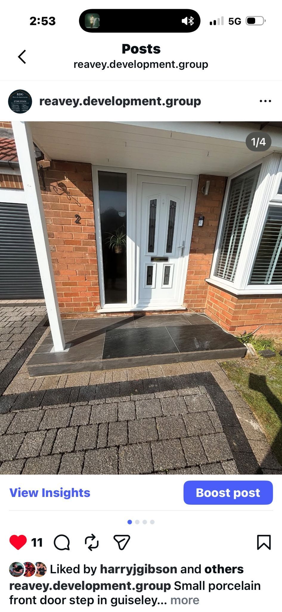 Front door of a brick house with white trim, a paved path, and sunlight on the entryway