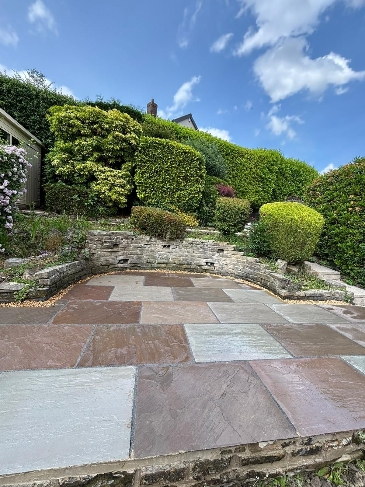 Stone patio steps leading to a lush ivy-covered garden under a bright blue sky