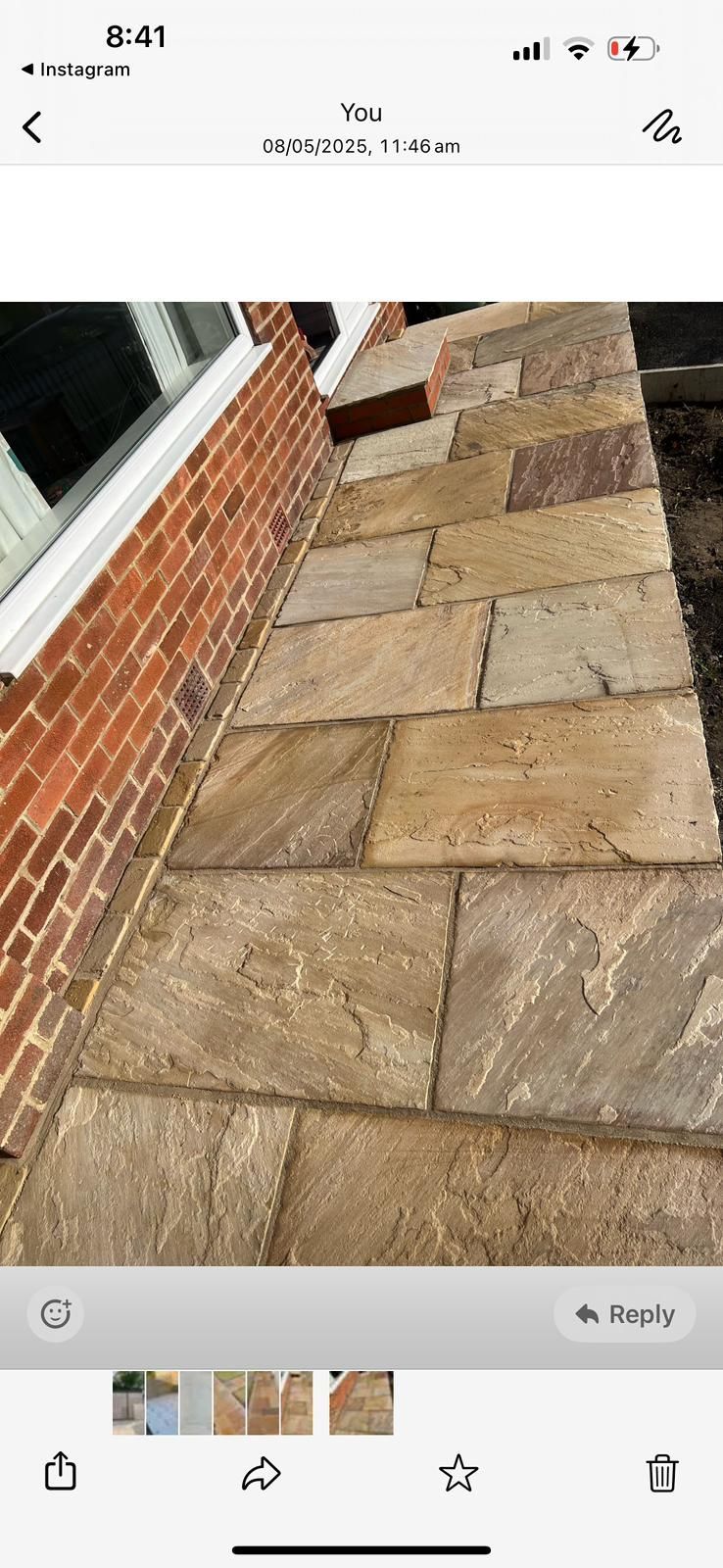 Stone patio beside a brick wall, with a sloped walkway and wet pavement.