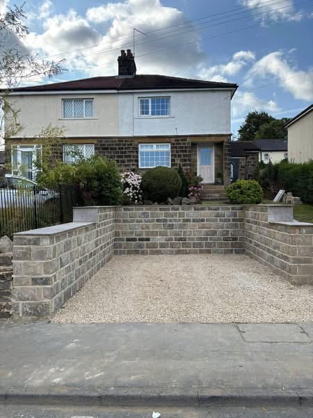Semi-detached house with new brick retaining walls and a gravel driveway under a cloudy sky