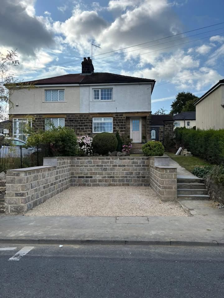 Semi-detached house with low brick wall, front garden, and steps leading to the sidewalk under a cloudy sky