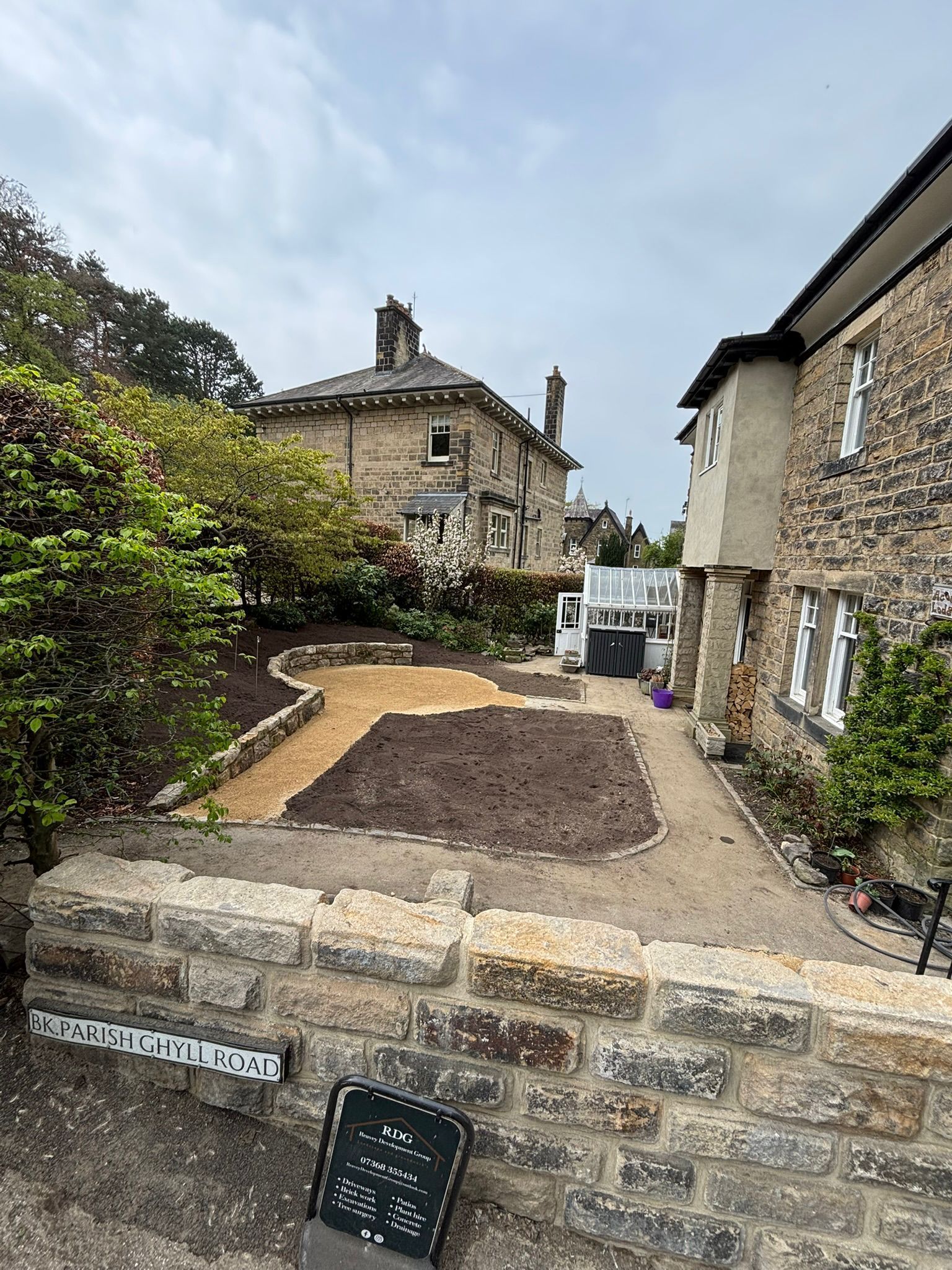 Stone cottages with a small front garden and paved path on a cloudy day