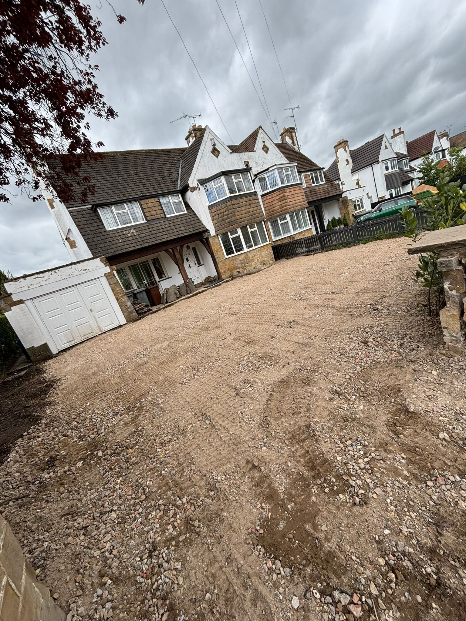 Tilted view of a gravel courtyard beside white houses under a cloudy sky