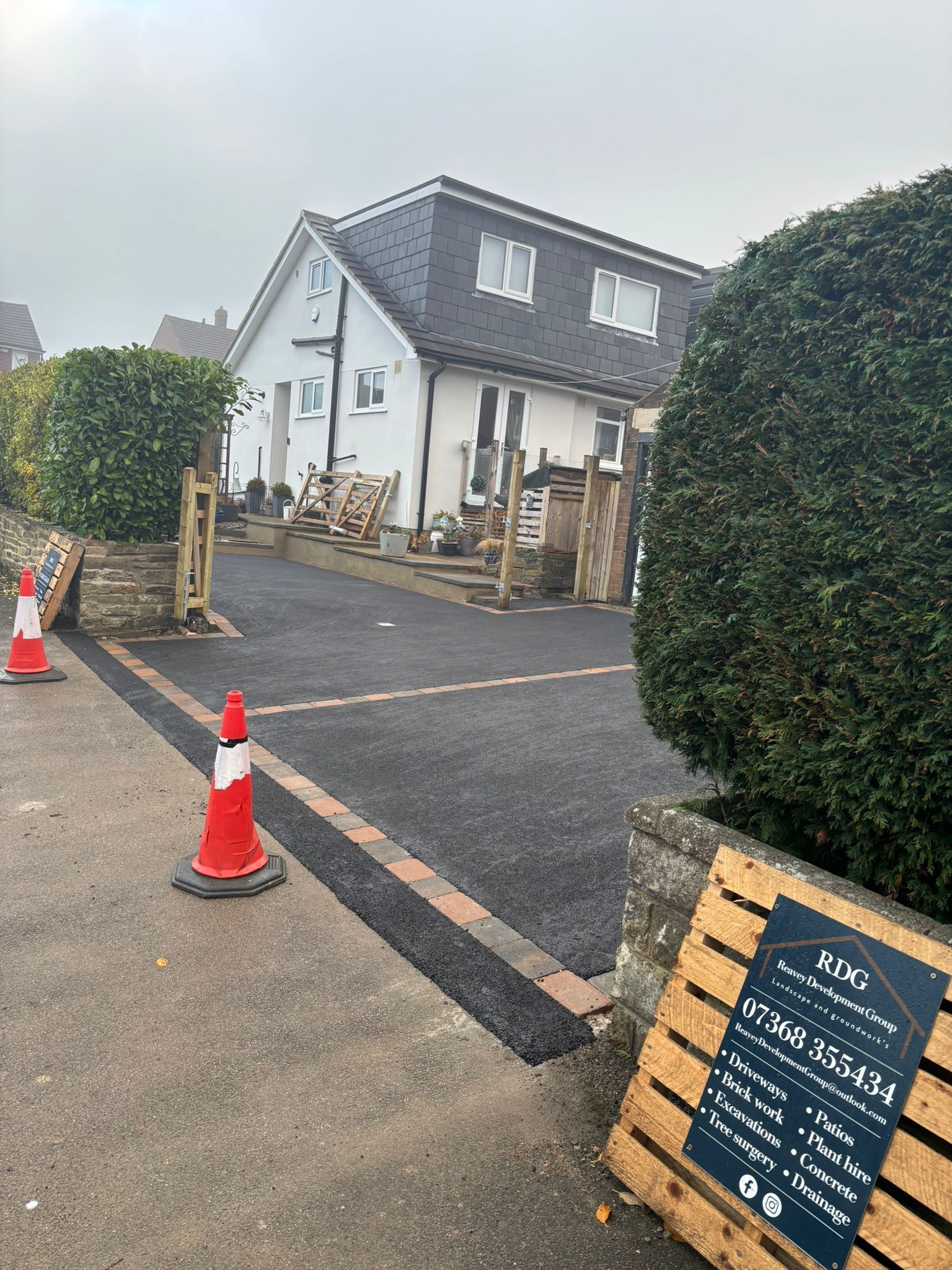 Outdoor café entrance with cones, rope barriers, a chalkboard sign, and a white building