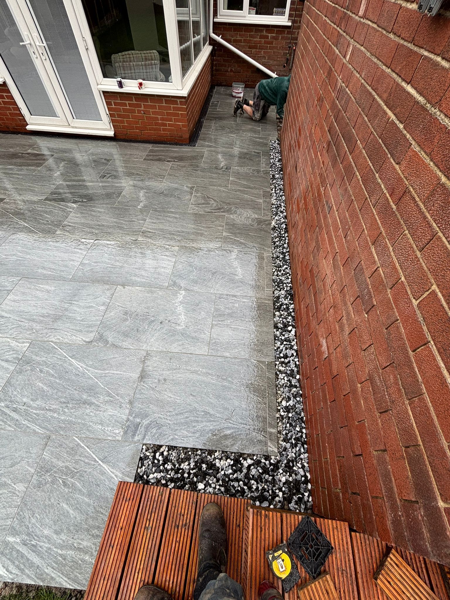 Narrow brick-lined outdoor walkway with concrete ground and a small gray dog near the far wall.