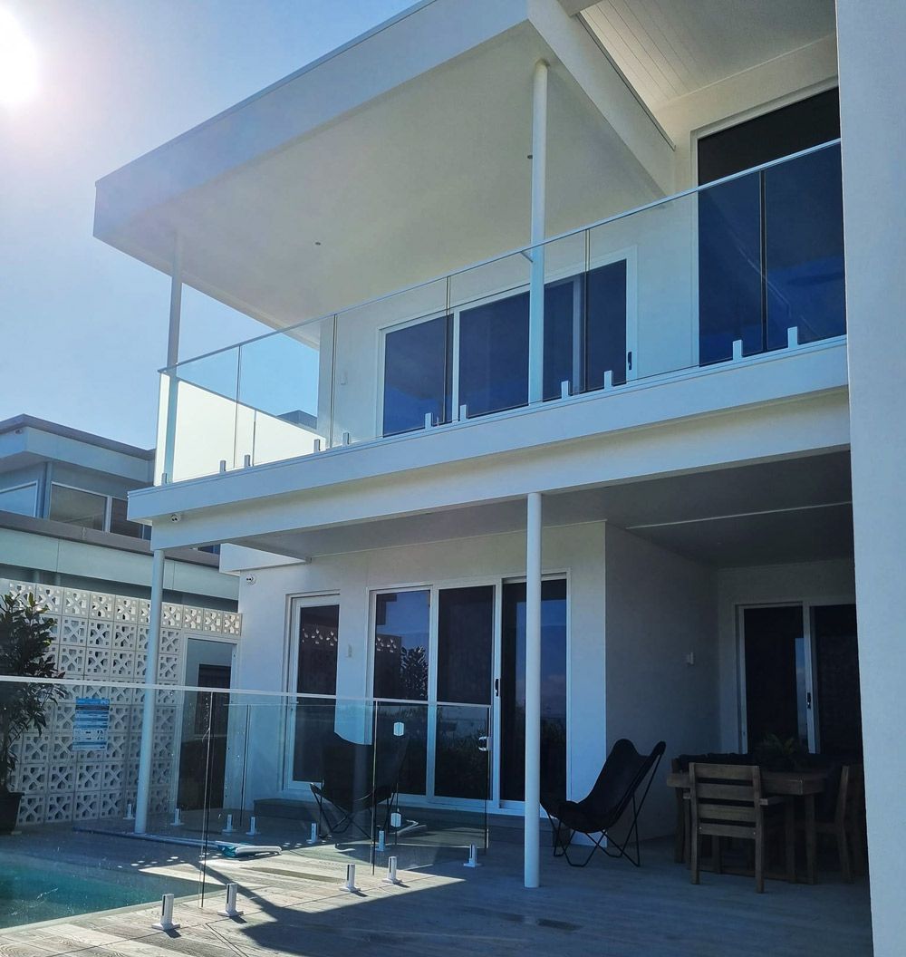 A Large White House With a Swimming Pool in Front of It — D & T Balustrade Systems In Unanderra, NSW