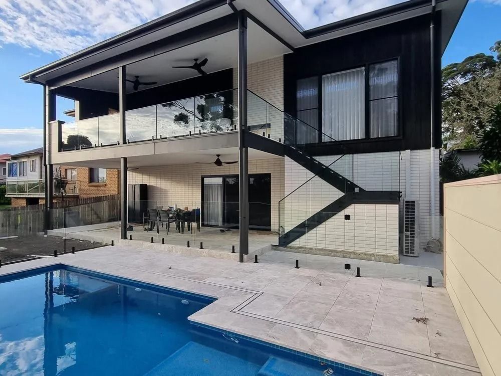 A Large House With a Swimming Pool in Front of It — D & T Balustrade Systems In Unanderra, NSW