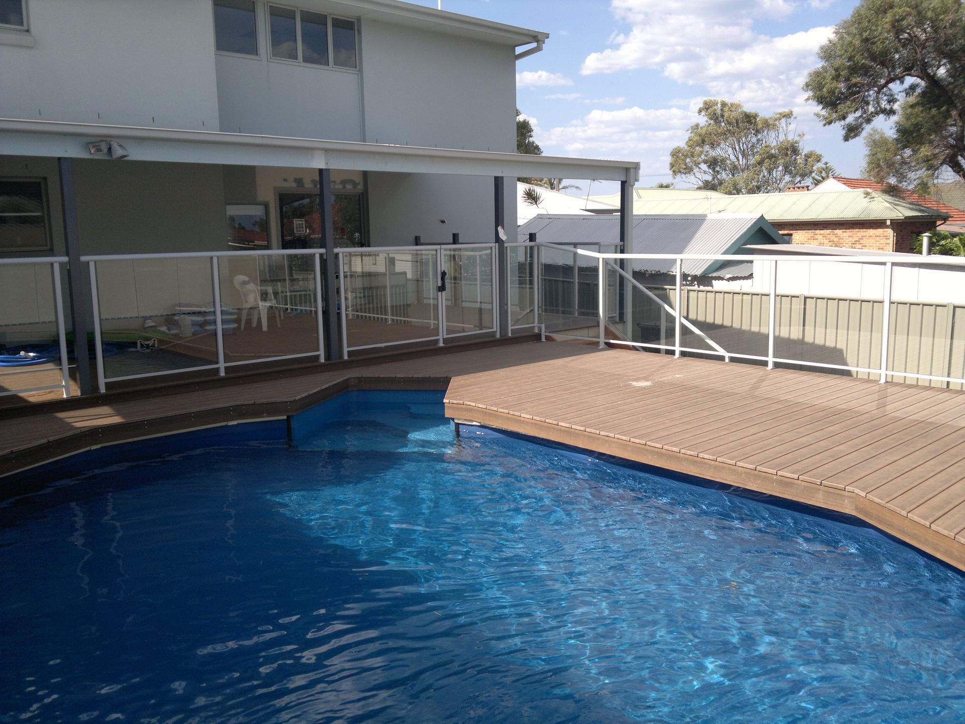 A Fence Surrounds a Swimming Pool in a Backyard — D & T Balustrade Systems In Bulli, NSW
