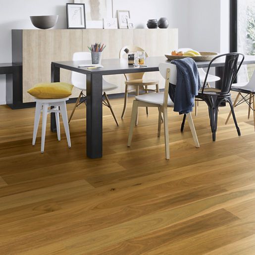 Dining room with hardwood floors and a table set for a meal, chairs of various styles surrounding it.