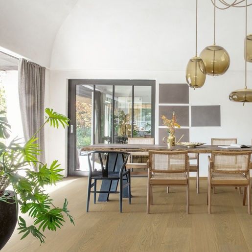 Dining room with wood table, rattan chairs, and globe pendant lights. A large plant sits in the foreground.