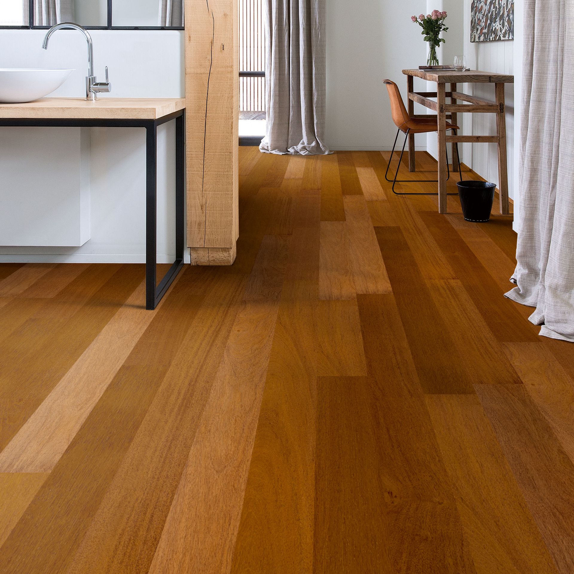 Wooden floor in a room with a sink, desk, curtains, and plants. The floor has a warm, brown tone.