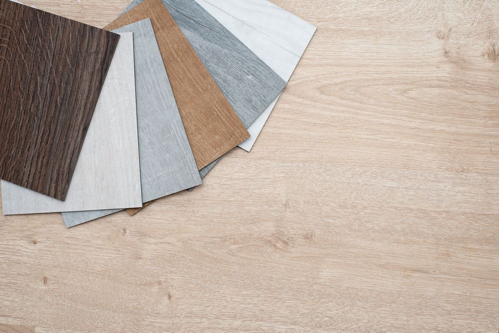 Wood flooring samples fanned out on a light wood surface, displaying various shades and textures.