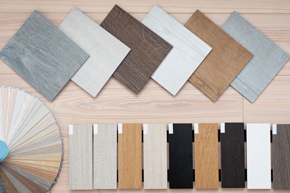 Samples of various wood flooring options displayed on a light wooden surface, including square and rectangular pieces in different colours and grains.
