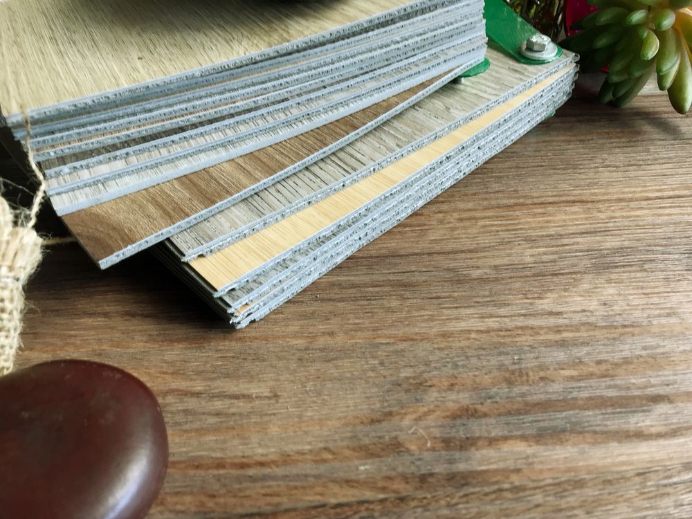 Stack of wood flooring samples in various shades on a wooden table.