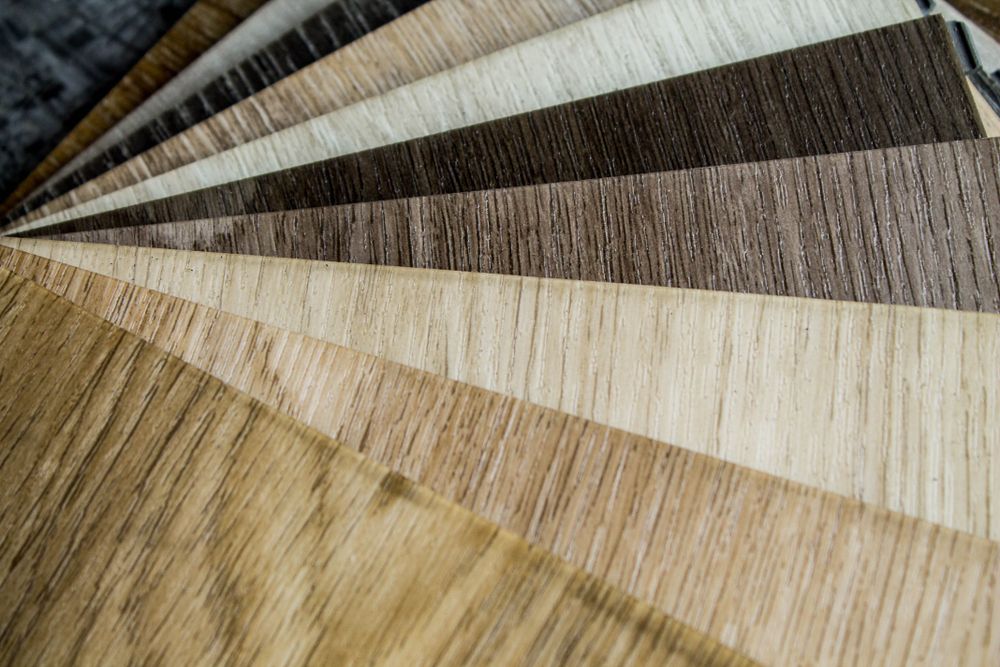 Variety of wood flooring samples fanned out, showcasing different colours and grain patterns, ranging from light to dark brown.