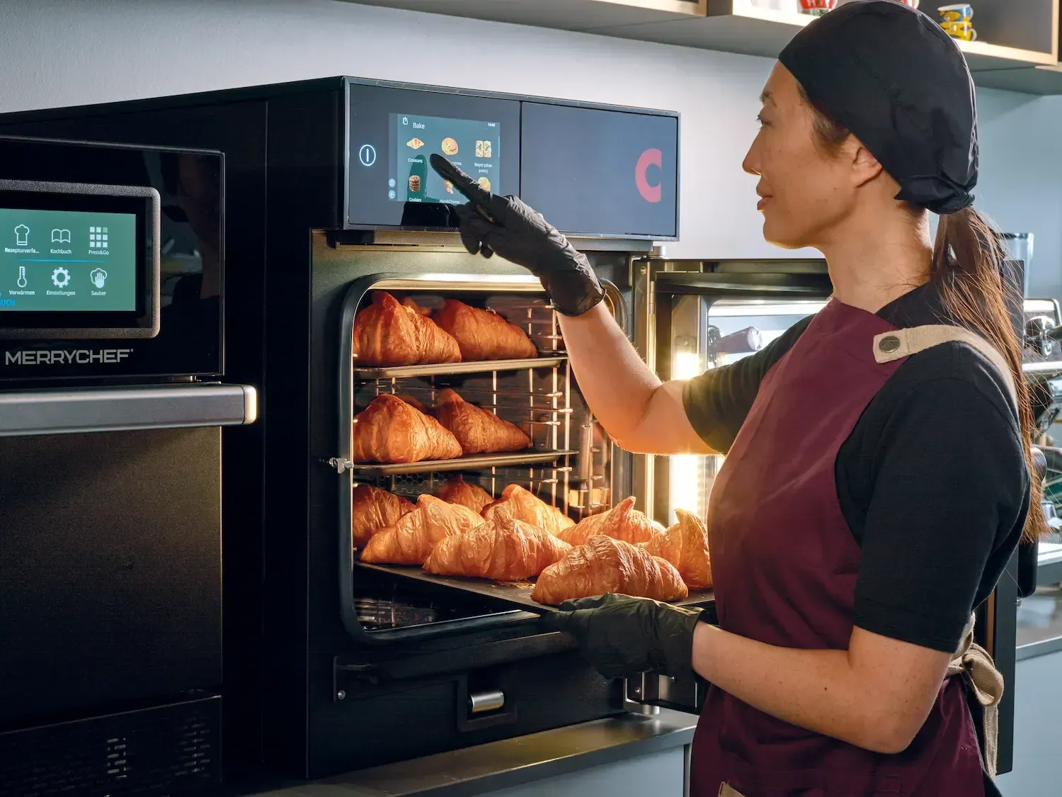 Een vrouw haalt een schaal croissants uit de oven.