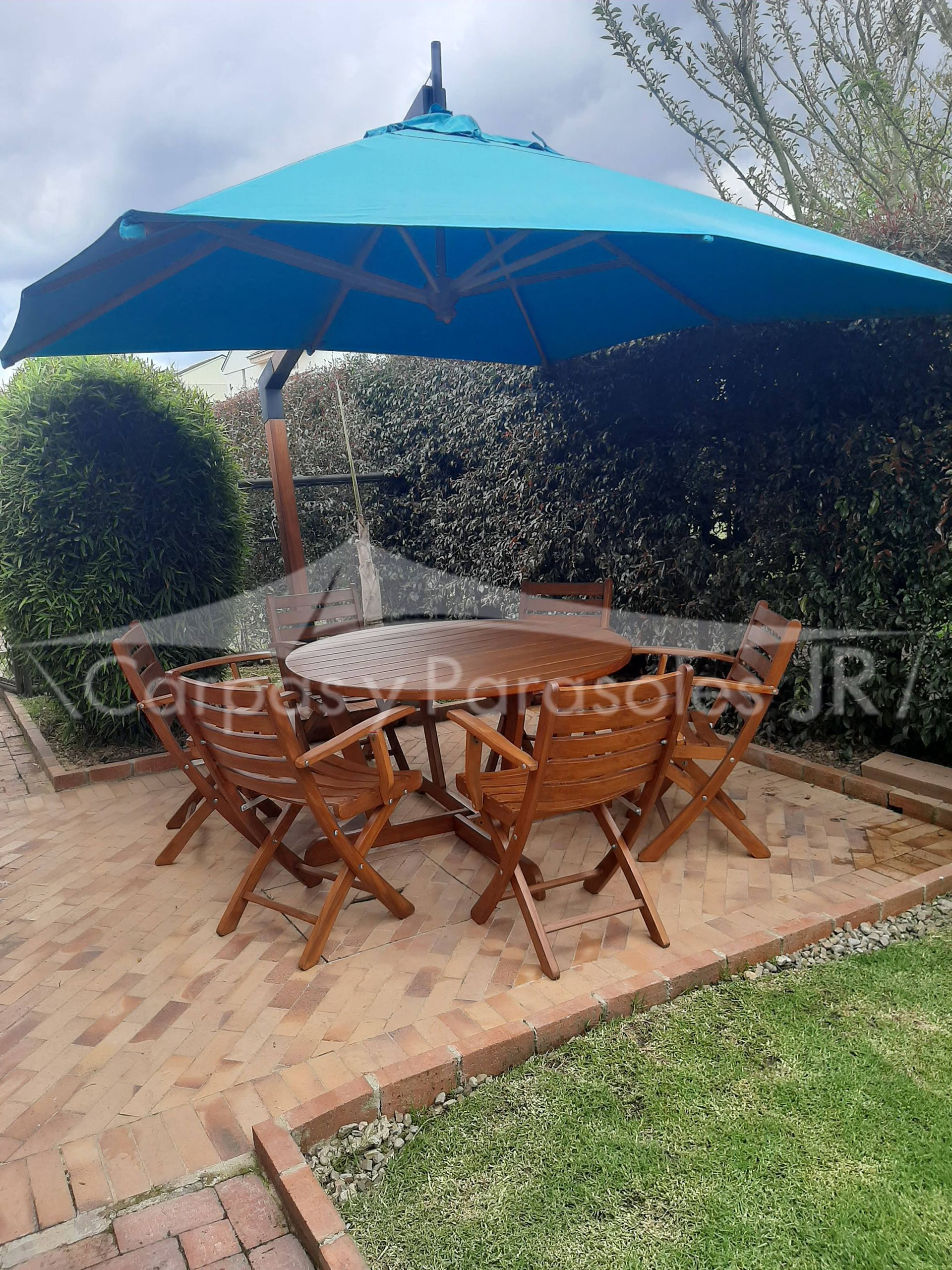 Un conjunto de muebles de patio con una mesa redonda de madera y cuatro sillas a juego