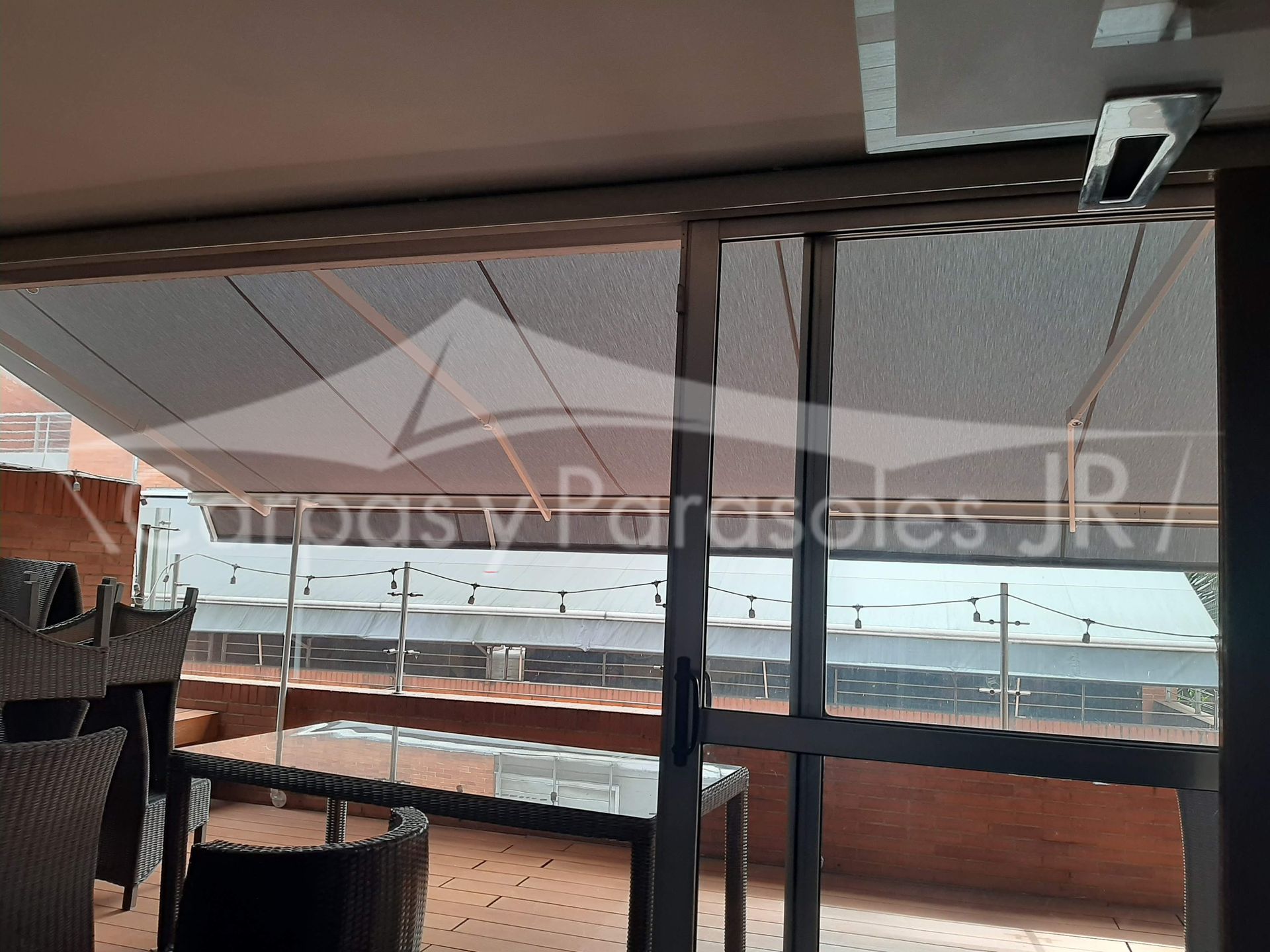 Un toldo retráctil para exteriores se extendía sobre un balcón con muebles de mimbre