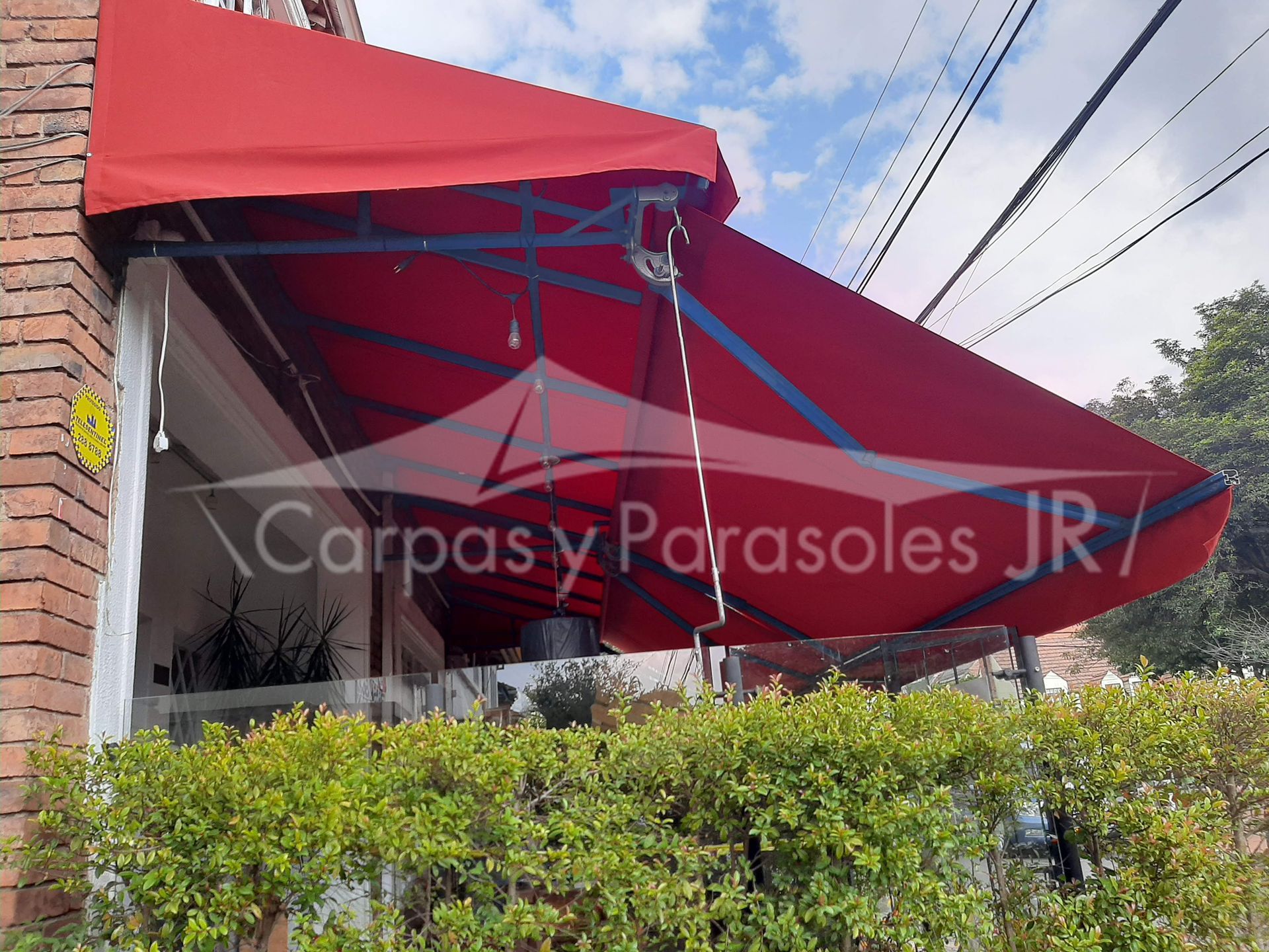 Un toldo retráctil de color rojo se extiende sobre un patio exterior