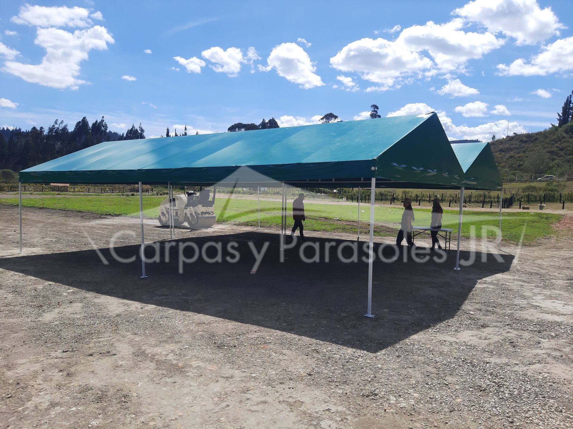 Una gran tienda de campaña verde se alza sobre un campo de grava al aire libre