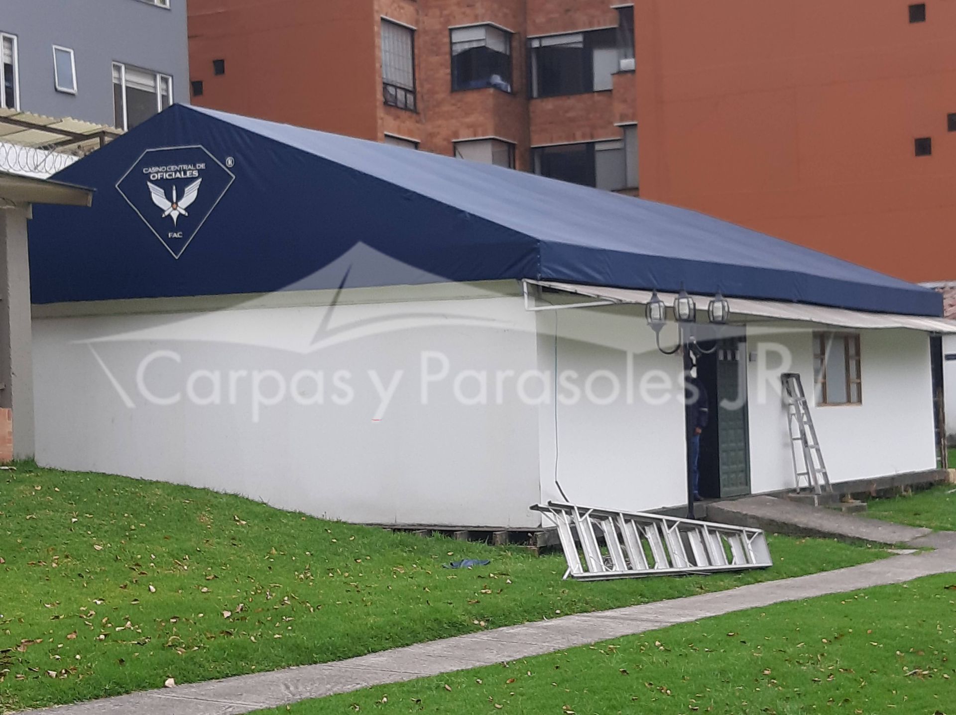 Un edificio blanco con un gran techo de lona azul, que muestra el logotipo de la empresa
