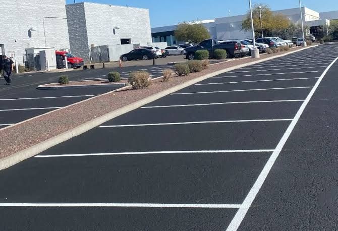 Empty parking lot with painted white lines beside a modern building on a sunny day