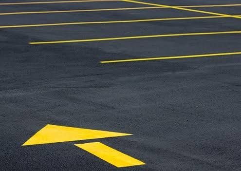 Empty asphalt parking lot with yellow directional arrows painted on the ground