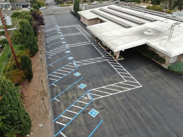 Empty parking lot with blue accessible parking markings beside a low building and covered entrance