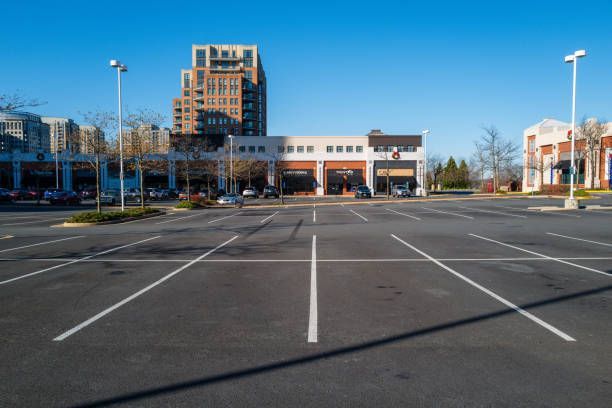 Empty parking lot with a low brick building and tall office tower in the background on a clear day