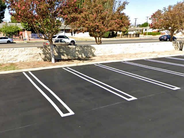 Empty parking lot spaces with fresh white lines near a stone wall and trees