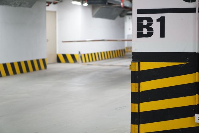 Empty underground parking garage with black-and-yellow striped barriers and a B1 pillar.