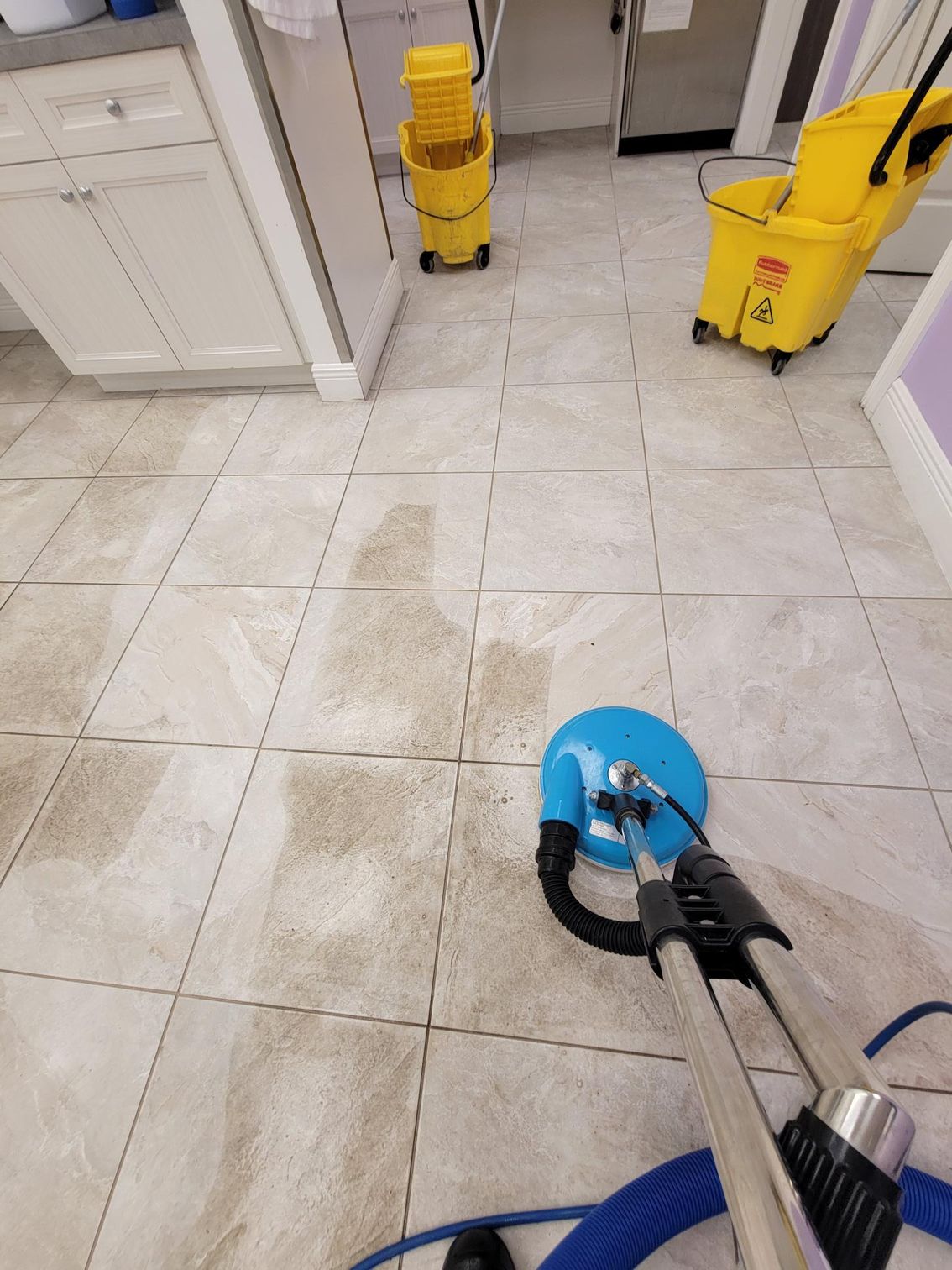 A man is cleaning a tile floor with a vacuum cleaner.