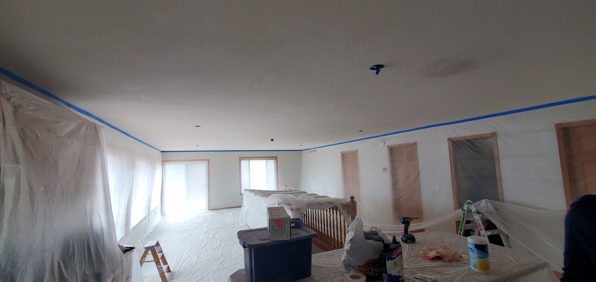 Renovation room with plastic-covered walls, ceiling tape, and construction tools scattered around