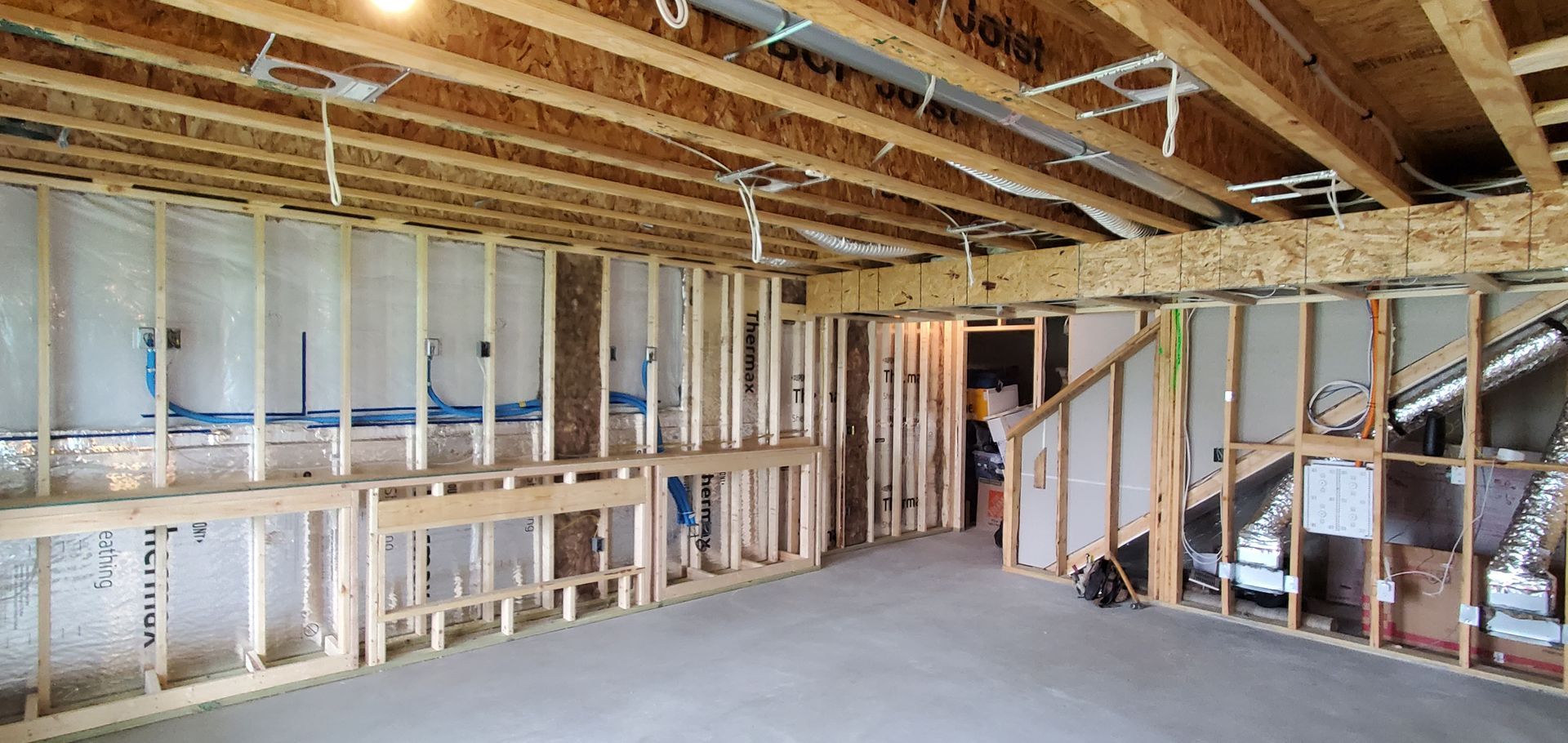 Interior of a house under construction with exposed wooden framing and concrete floor