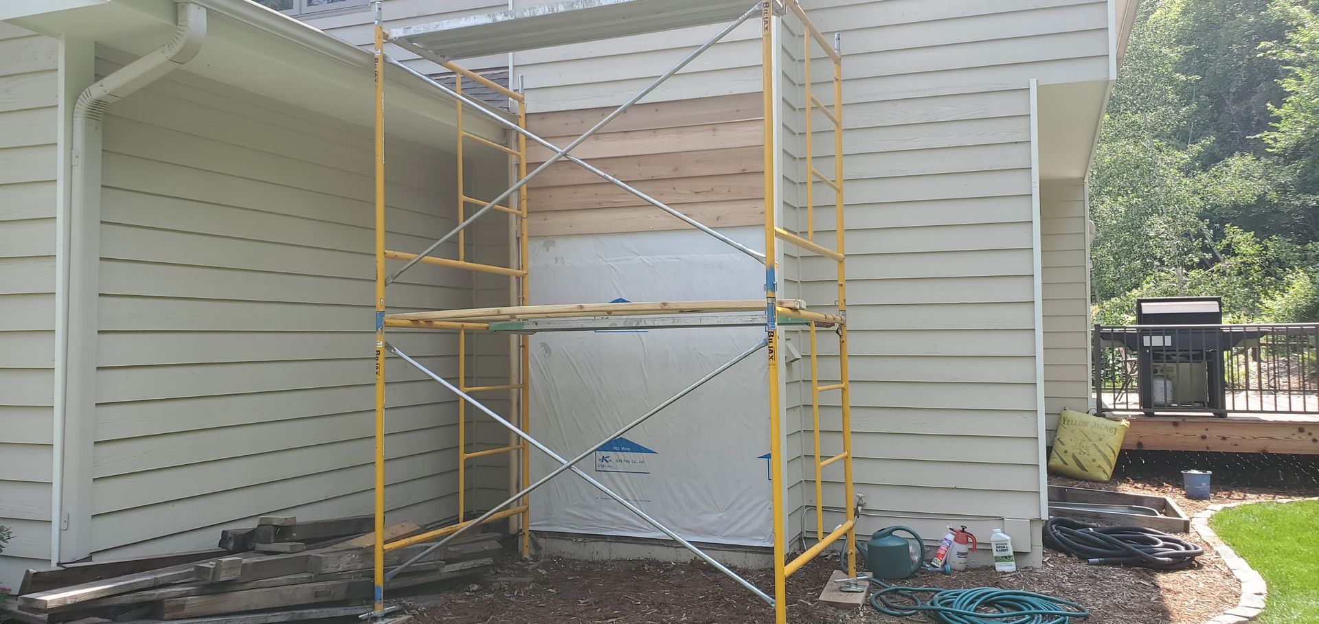 Yellow scaffolding beside a house exterior with a covered doorway under renovation