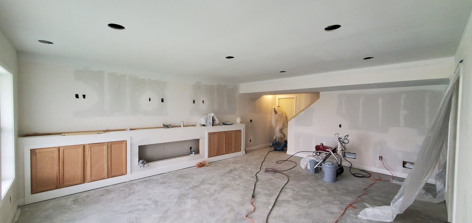 Unfinished living room with white cabinets, exposed floor, and construction materials scattered around.