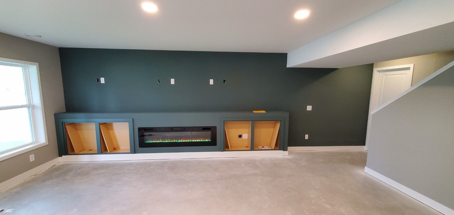 Empty living room with dark accent wall, built-in fireplace, gray carpet, and white ceiling lights