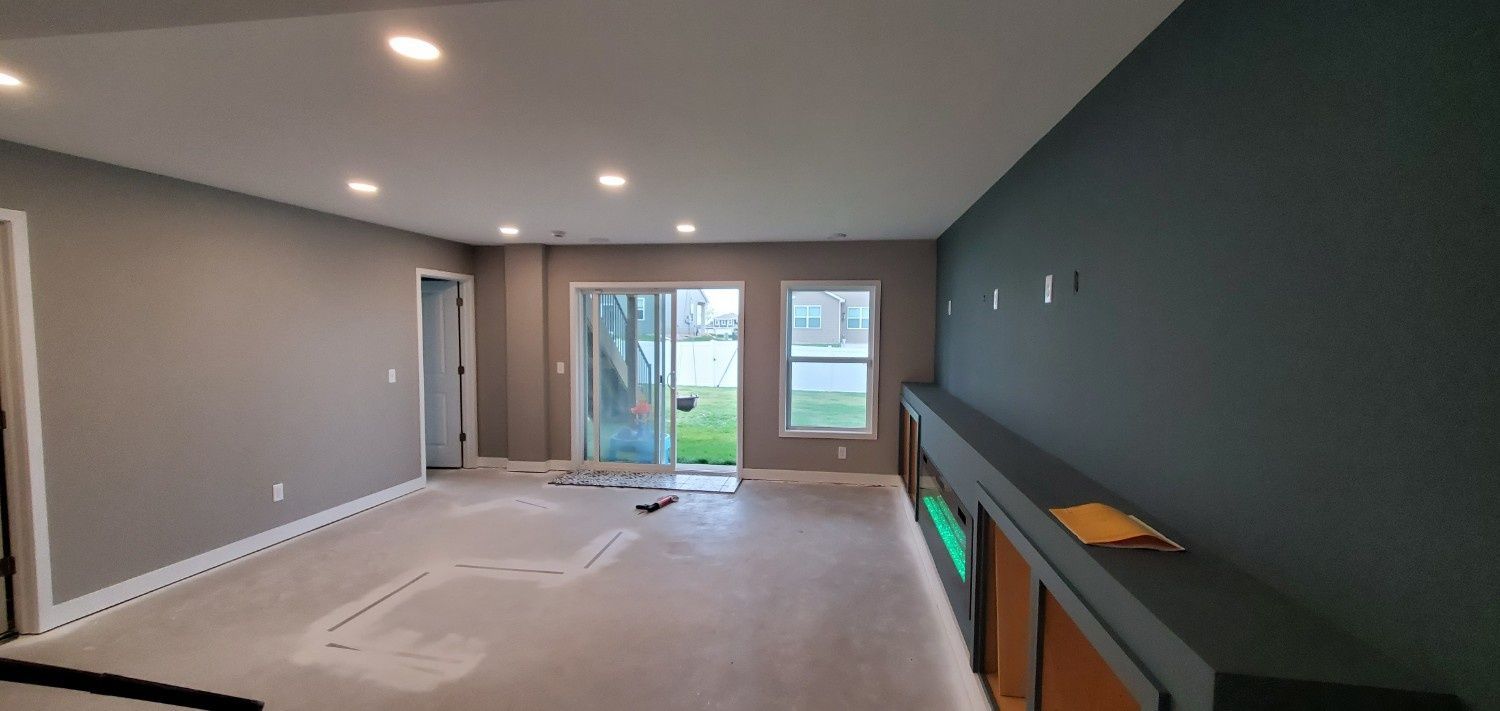 Empty living room with gray walls, recessed lights, and sliding glass doors to a backyard.