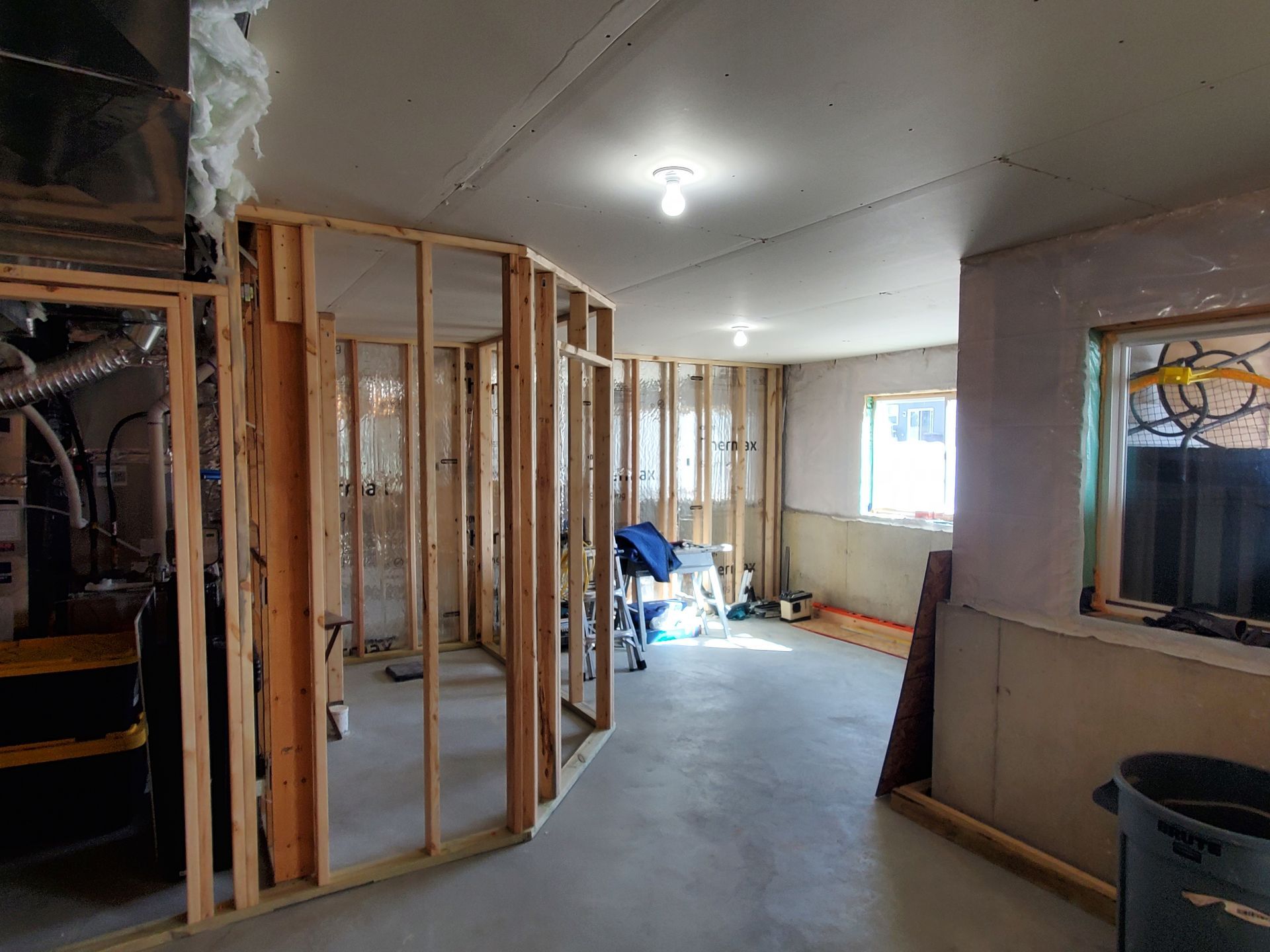 Partially framed interior room under construction with exposed studs, drywall, and debris on the floor