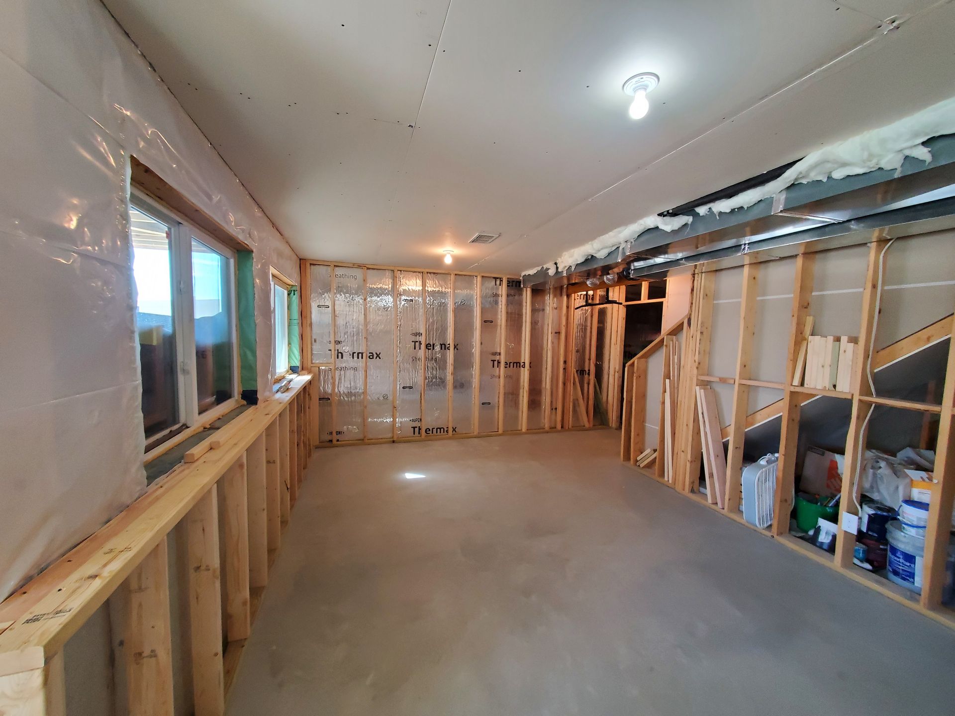 Partially renovated room with exposed studs, drywall, and a concrete floor under construction