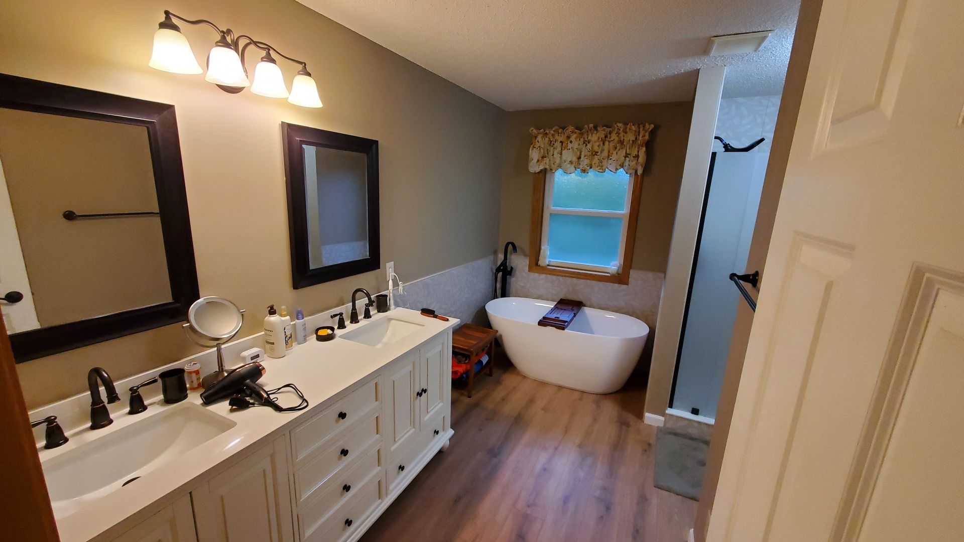 Bathroom with double vanity, large mirror, tub, and shower in warm wood tones