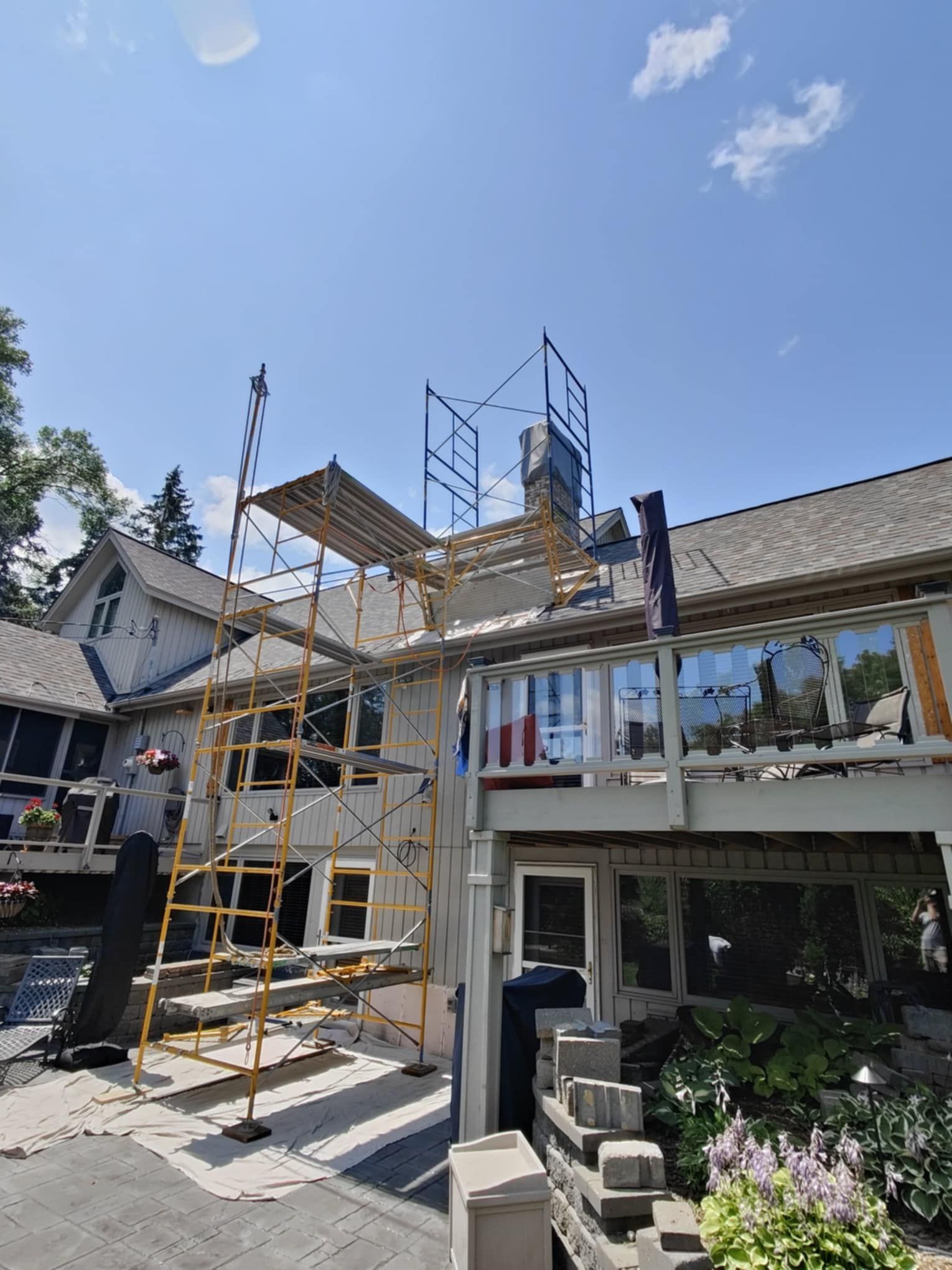 House exterior with scaffolding during roof renovation under a clear blue sky