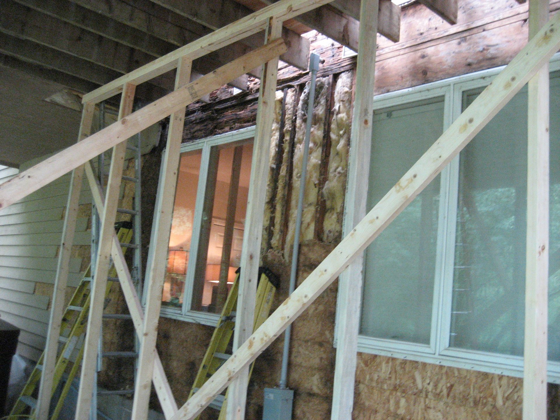 Scaffolded wooden wall with windows and exposed insulation at a building construction site