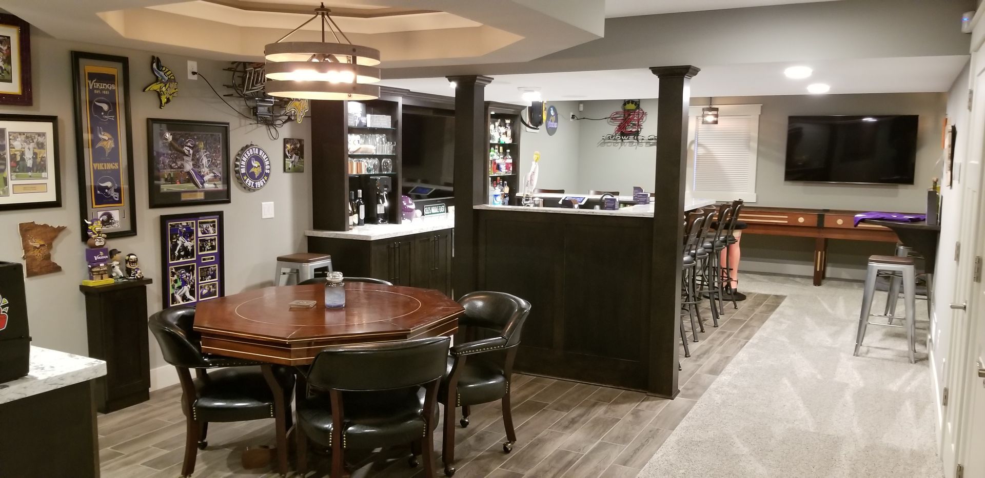 Basement rec room with bar, round table, pool table, and wall art