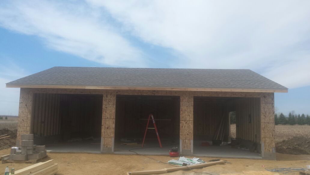 Single-story brick building under construction with a wide front porch and open doorways.