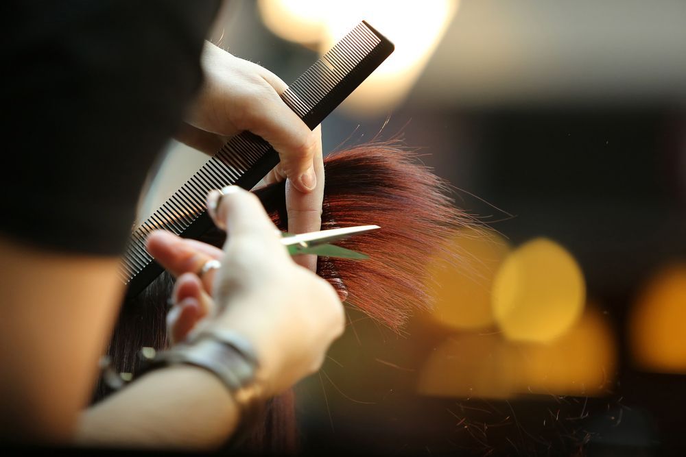 A Woman is Getting Her Hair Cut by a Hairdresser — Barbarella Hair in Maryborough, QLD