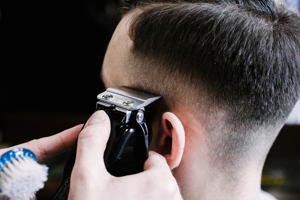 A Man is Getting His Hair Cut by a Barber With a Clipper — Barbarella Hair in Maryborough, QLD