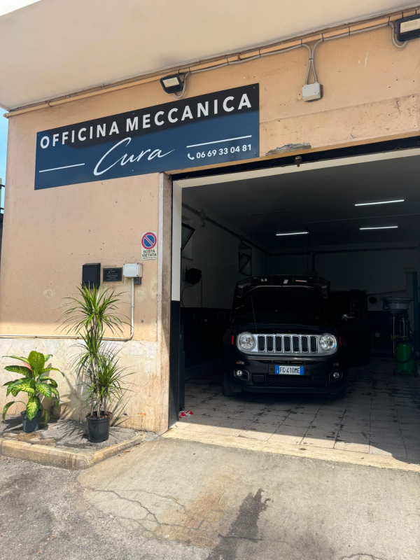 Ingresso di un'officina meccanica con un SUV scuro parcheggiato all'interno del garage e insegna con la scritta