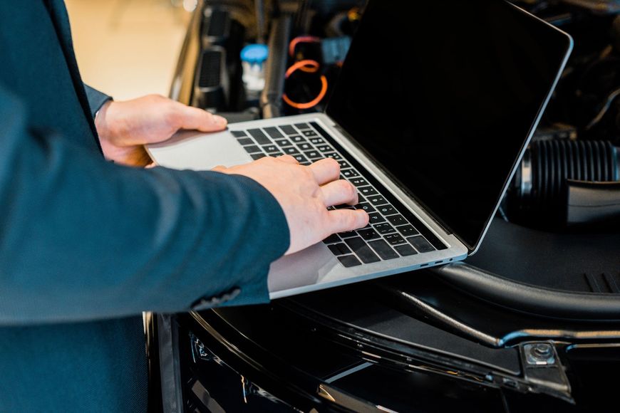 Mani che digitano su un laptop con schermo scuro all'interno di un veicolo.
