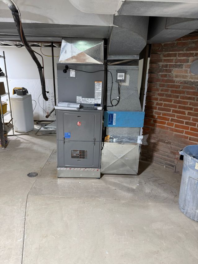 A man is working on an air conditioner outside of a brick building.